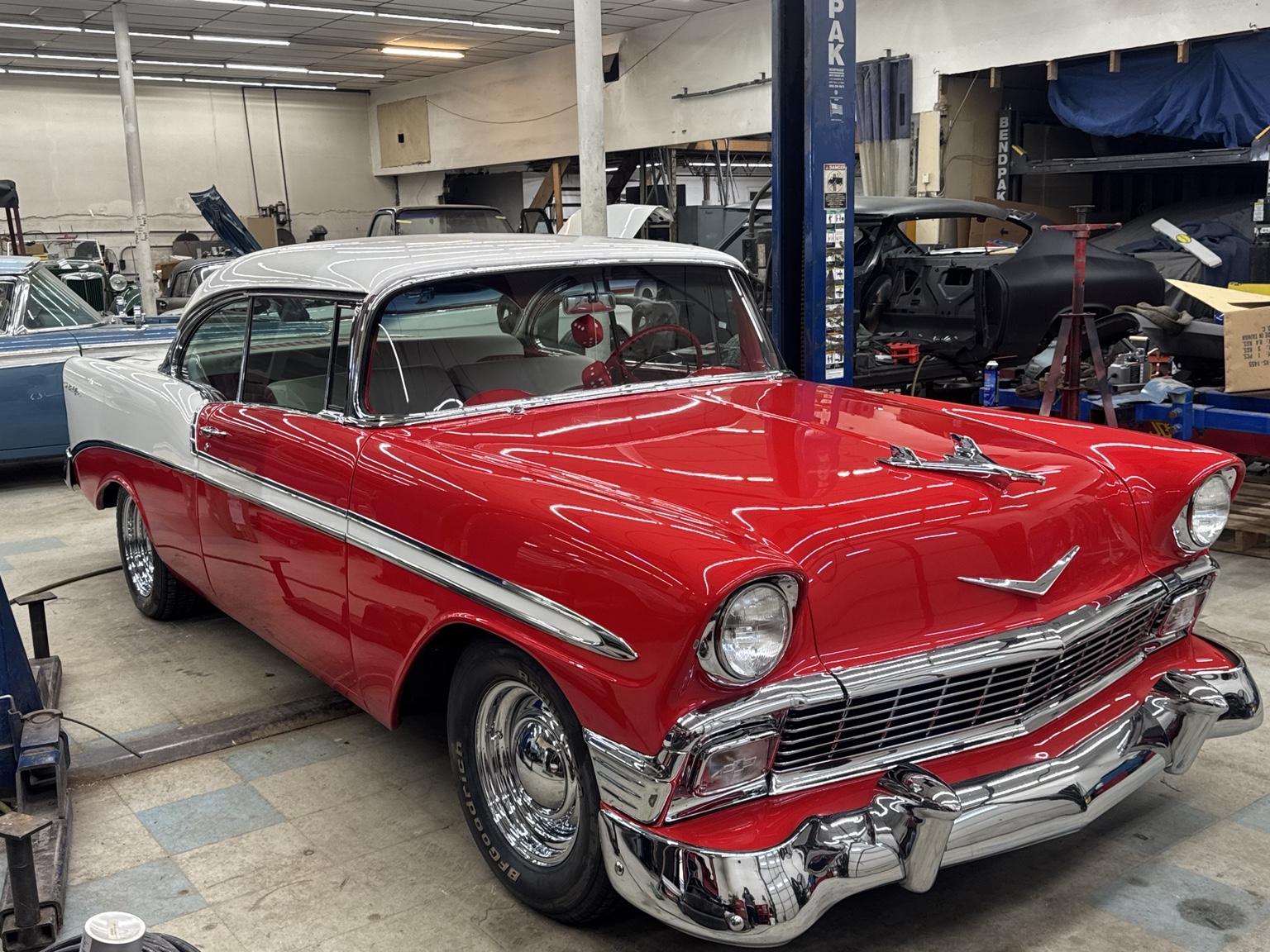 A restored red and white classic car inside the Classic Rods shop